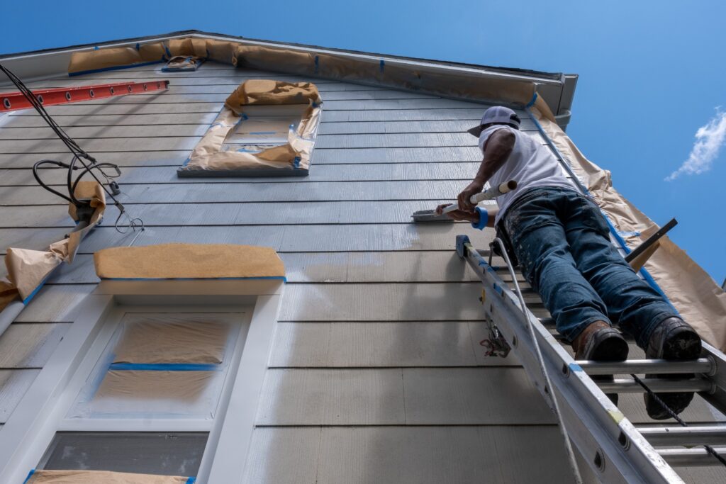 One of the best questions to ask before hiring a painting contractor is if they offer a warranty. Image of a professional house painter at work.
