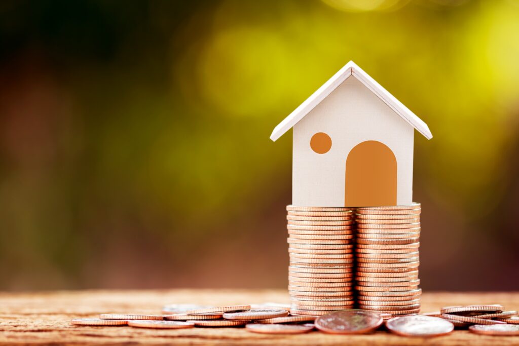 model of a house on a stack of coins to show concept of increasing home values