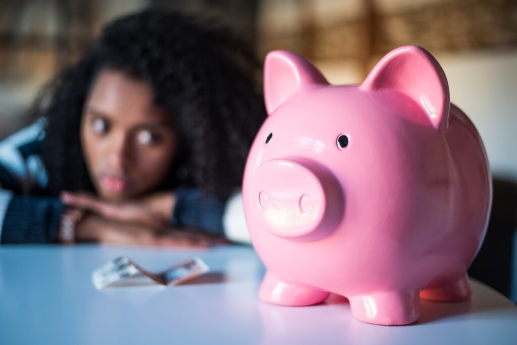 woman looking at piggy bank with sadness and frustration