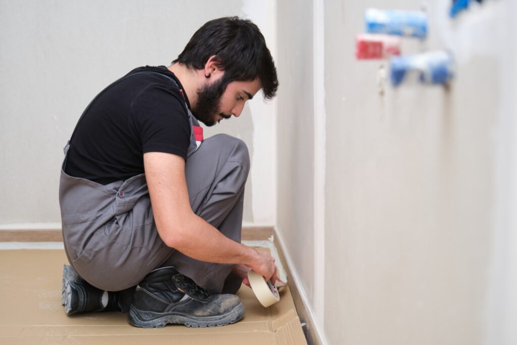 Image of professional painter taping baseboards.