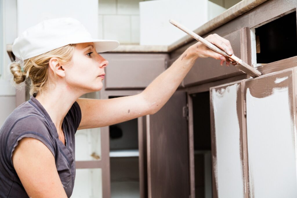 Image of woman painting cabinets with a brush and not getting good results.