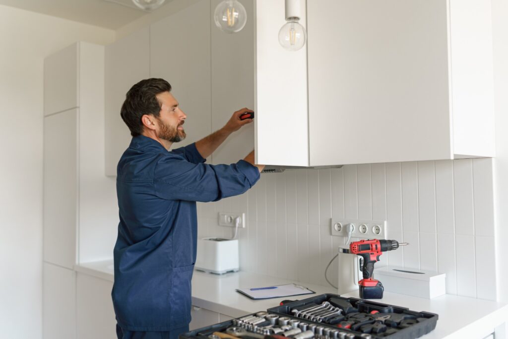 Image of male professional cabinet painter removing cabinets from wall