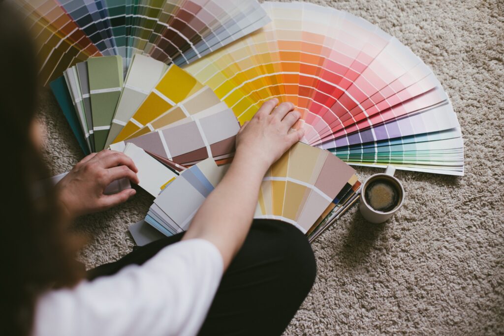Image of woman sitting on the floor with a cup of coffee and many paint swatches.
